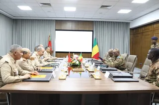 Des officiers marocains et maliens autour d'une table de réunion, devant les drapeaux des deux pays