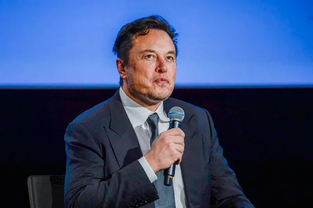 Elon Musk s’exprimant au micro devant un fond bleu