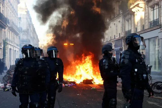 Des policiers casqués devant un feu de barricade dans une rue de Paris