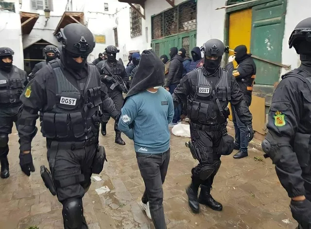 Des agents de la DGST escortent un suspect à la tête couverte lors d'une précédente opération