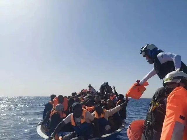 Des sauveteurs distribuent des gilets de sauvetage à des migrants sur une embarcation surchargée en mer