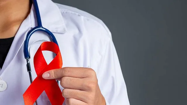 La main d'un médecin en blouse blanche avec stéthoscope tenant un ruban rouge, symbole de la lutte contre le sida, image d'archives