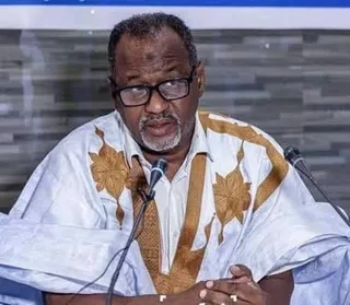 Un responsable syndical en boubou blanc s'exprime devant des micros