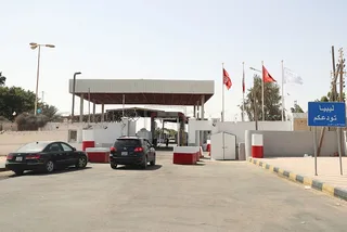 L'entrée d'un poste-frontière terrestre entre la Tunisie et la Libye, avec des voitures et un panneau « La Libye vous dit au revoir », photo d'archives