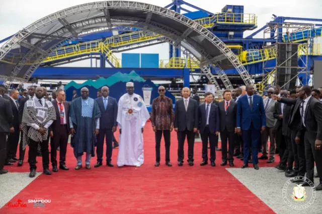 Des officiels posent sur un tapis rouge devant des installations industrielles lors du lancement du projet minier Simandou en Guinée
