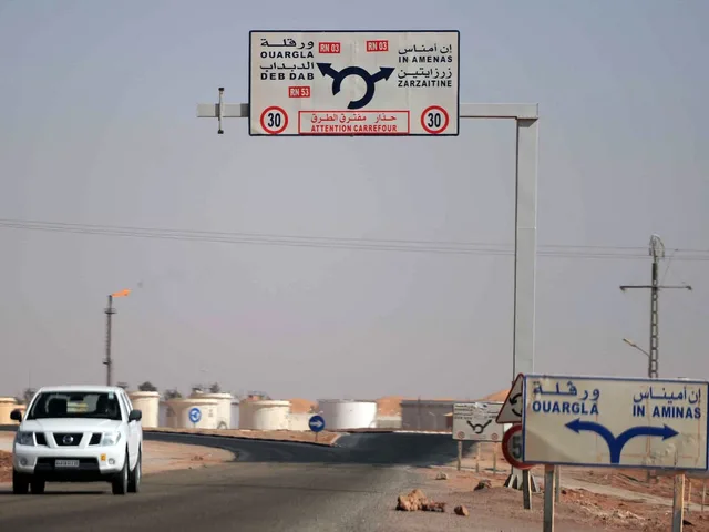Panneaux routiers en arabe et en français indiquant Debdeb, Ouargla et In Amenas, avec un véhicule sur la route, photo d'archives