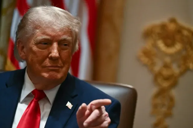 Le président américain Donald Trump, assis, pointe du doigt devant le drapeau américain, photo d'archives