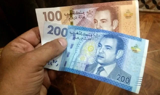 Une main tient deux billets marocains de 100 et 200 dirhams, photo d'archives