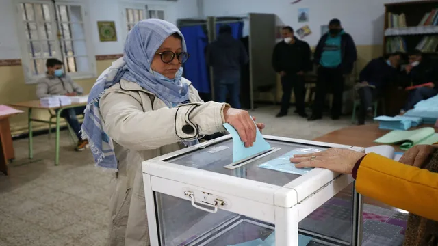 Une femme glissant un bulletin dans une urne transparente dans un bureau de vote en Algérie, photo d'archives