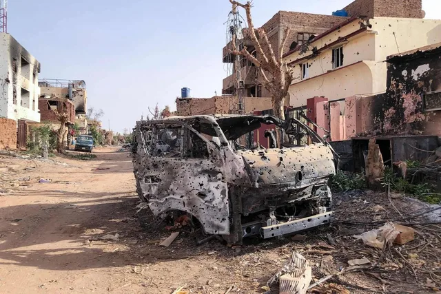 Carcasse d'un véhicule brûlé et criblé d'impacts dans une rue endommagée par la guerre au Soudan, photo d'archives