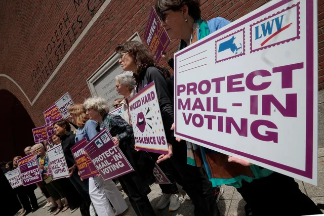 Des manifestantes brandissent des pancartes en faveur du vote par correspondance