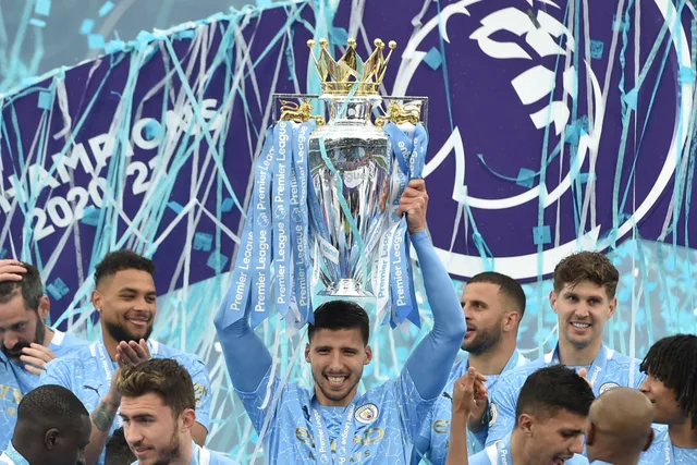 Des joueurs de Manchester City en maillot bleu ciel soulèvent le trophée de la Premier League sous des serpentins, photo d'archives