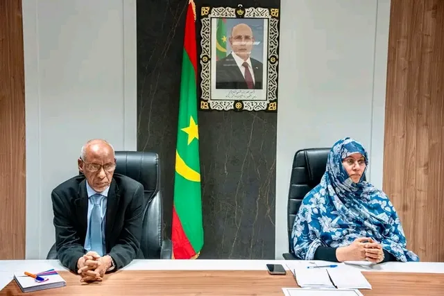 Deux responsables assis à une table de réunion devant le drapeau mauritanien