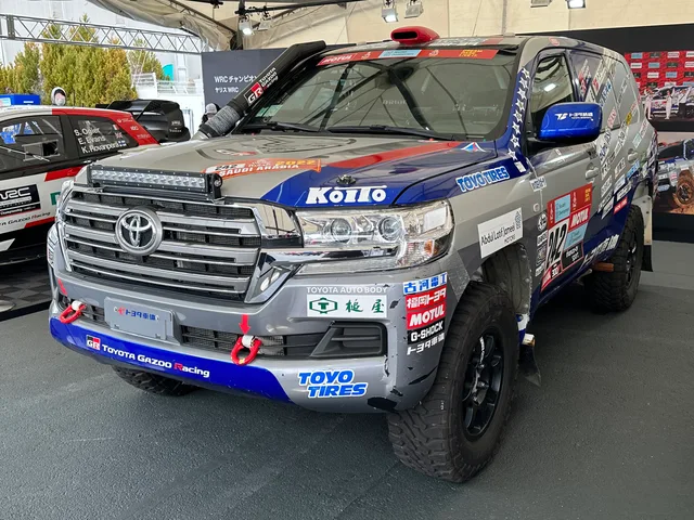 Une voiture de rallye aux couleurs du Dakar 2022 exposée sous un stand