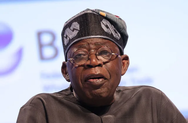 Le président nigérian Bola Tinubu, coiffé d'un bonnet traditionnel et portant des lunettes, s'exprimant lors d'une conférence, photo d'archives