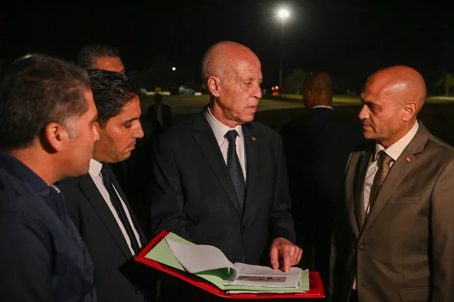 Le président tunisien Kaïs Saïed consulte un dossier entouré de responsables, de nuit, photo d'archives