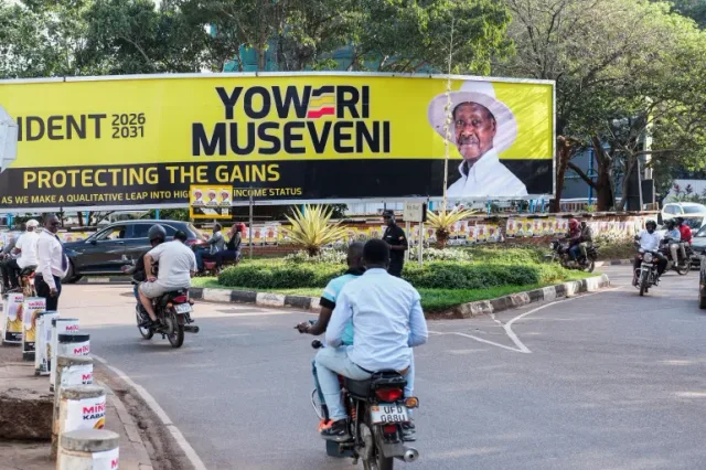 Des motos et des voitures dans une rue de Kampala près d'un grand panneau électoral, photo d'archives