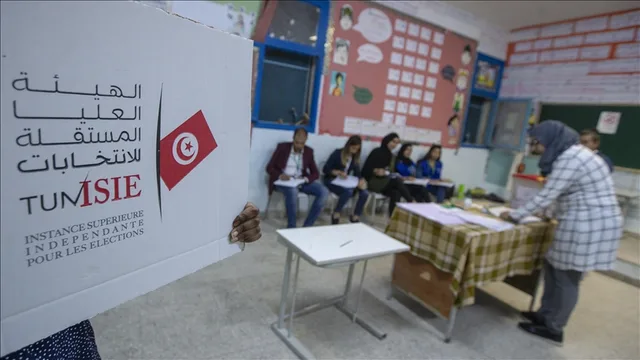 Un isoloir au logo de l'ISIE et des membres d'un bureau de vote dans une salle de classe, photo d'archives