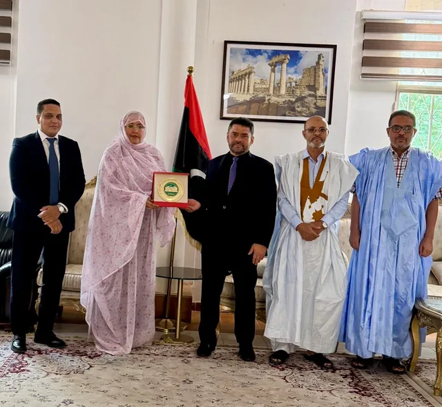 Des parlementaires remettent une plaque à l'ambassadeur devant le drapeau libyen