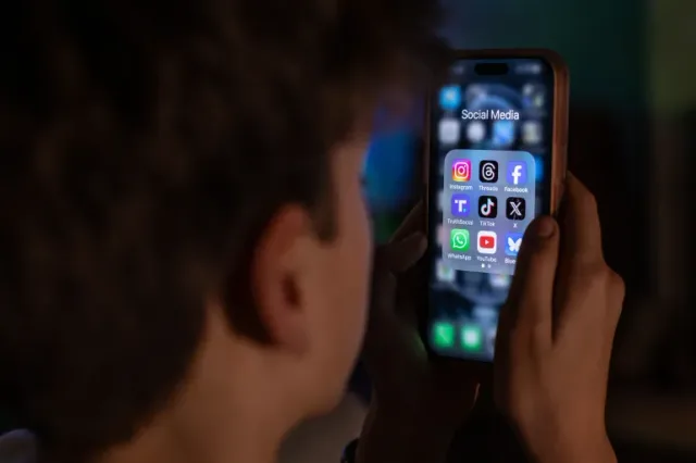 Une personne tient un téléphone affichant des applications de réseaux sociaux, photo d'archives