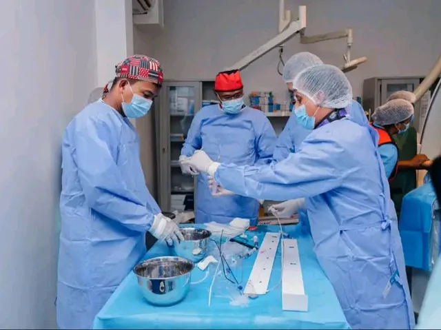Des médecins en tenue de bloc préparent du matériel dans une salle de cathétérisme
