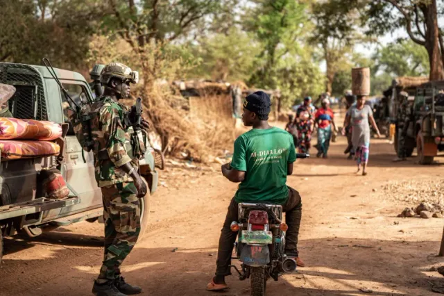 Un soldat sénégalais en tenue camouflée et casque près d'un pick-up sur une piste, image d'illustration d'archives