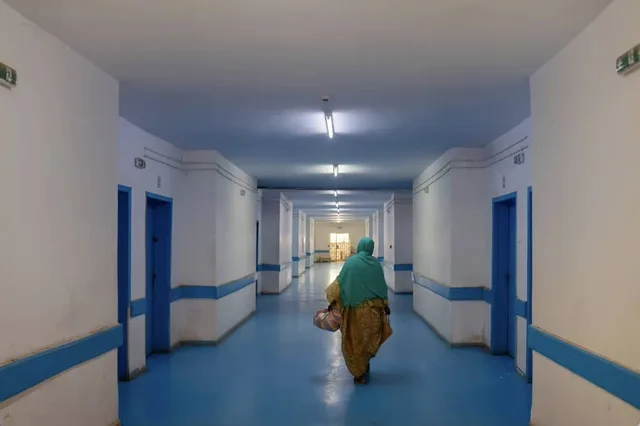 Un long couloir d'hôpital où marche une femme