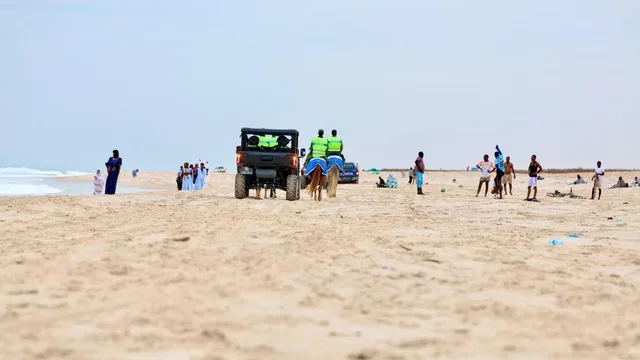 Une plage de sable à Nouakchott avec des promeneurs et un véhicule de patrouille