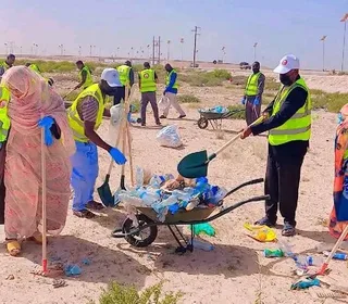 Des agents en gilets fluorescents ramassent des déchets plastiques dans une brouette