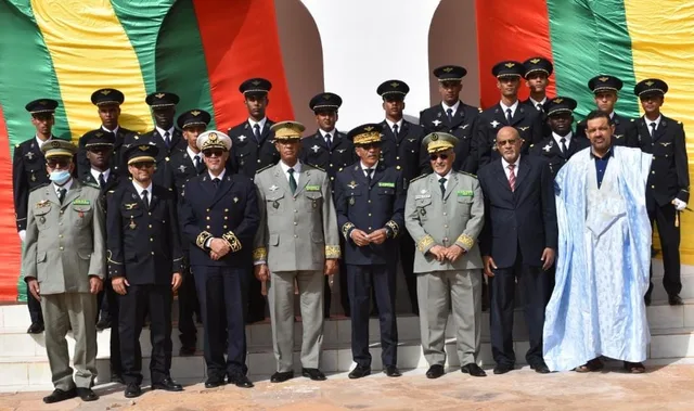 Des officiers et des responsables posent pour une photo de groupe devant le drapeau mauritanien