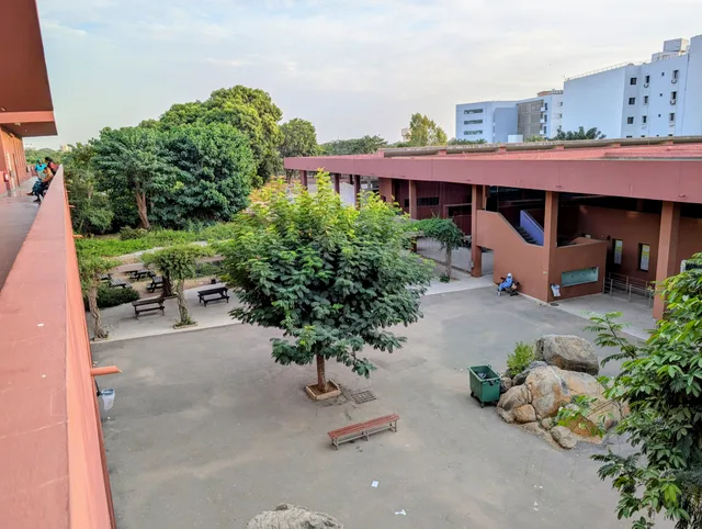 Cour d'un lycée de Dakar avec un arbre au centre et des bâtiments ocre, photo d'archives