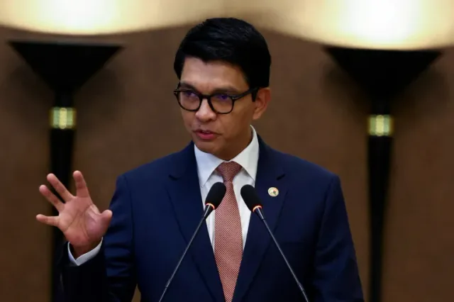Andry Rajoelina s'exprimant devant deux micros, en costume bleu et lunettes, photo d'archives
