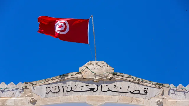 Le drapeau tunisien flotte au-dessus d'une façade en pierre portant l'inscription « Palais de justice » en arabe, photo d'archives