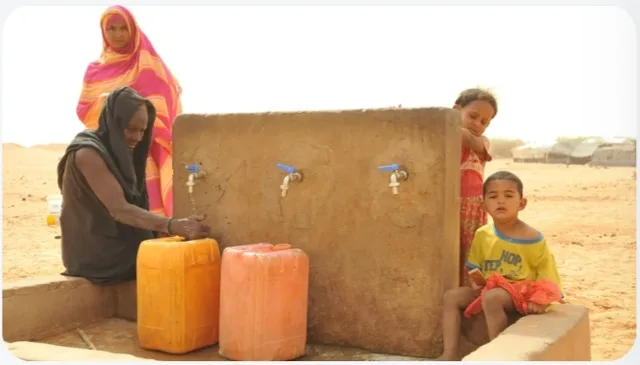 Des femmes et des enfants autour d'un point d'eau avec des bidons