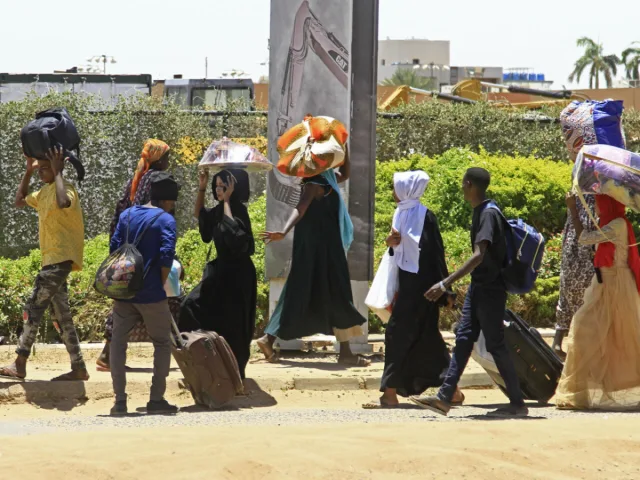 Hommes, femmes et enfants soudanais marchant au bord d'une route avec valises et ballots sur la tête, photo d'archives