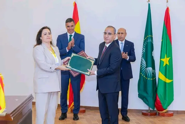 Les présidents Ghazouani et Sánchez applaudissent lors d'un échange de documents entre un responsable mauritanien et une responsable espagnole