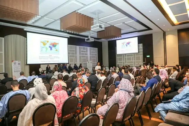 Des participants assis dans une salle de conférence face à des écrans
