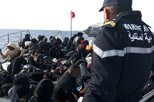 Un marin de la Marine royale marocaine près d'un groupe de migrants à bord d'une embarcation en mer, photo d'archives