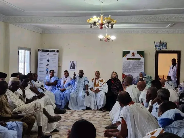 Des participants assis en cercle dans une salle de réunion, sous des banderoles politiques