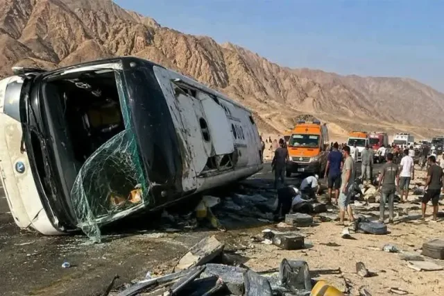 Un autocar couché sur le flanc au bord d'une route de montagne, entouré de secouristes et de passants, photo d'archives d'un accident en Égypte