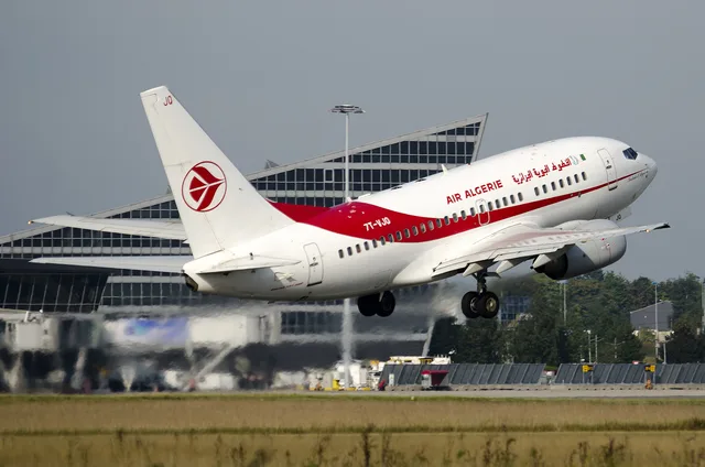 Un avion blanc et rouge d'Air Algérie au décollage depuis une piste d'aéroport