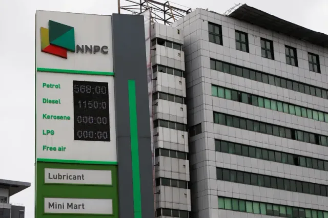 Le panneau des prix d'une station-service de la NNPC devant un immeuble de bureaux