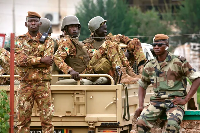 Des soldats maliens en tenue camouflée à bord et à côté d'un véhicule militaire, photo d'archives