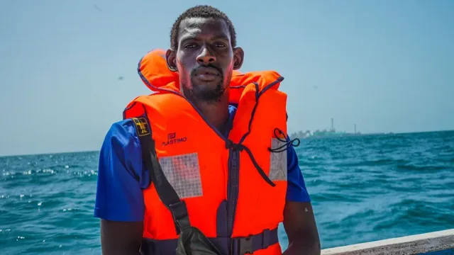 Un pêcheur portant un gilet de sauvetage orange à bord d'une embarcation en mer, photo d'archives