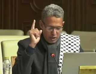 Un député portant des lunettes s'exprime au micro dans un hémicycle