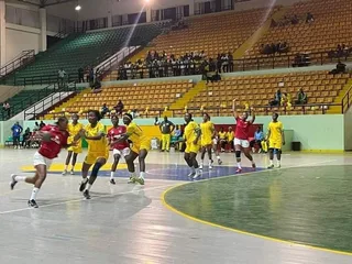 Des handballeuses en maillots rouges et jaunes pendant un match en salle, image d'illustration d'archives