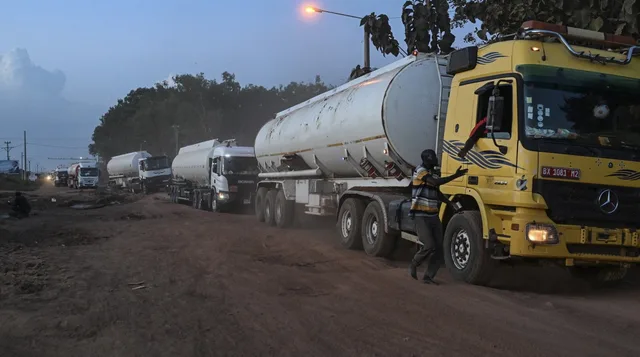 Une file de camions-citernes sur une piste en terre au crépuscule, image d'illustration d'archives