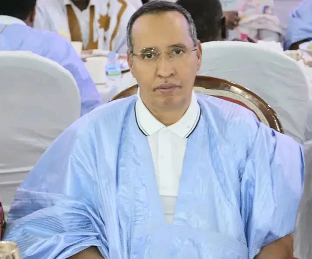 Un homme en boubou bleu clair assis lors d'une réception