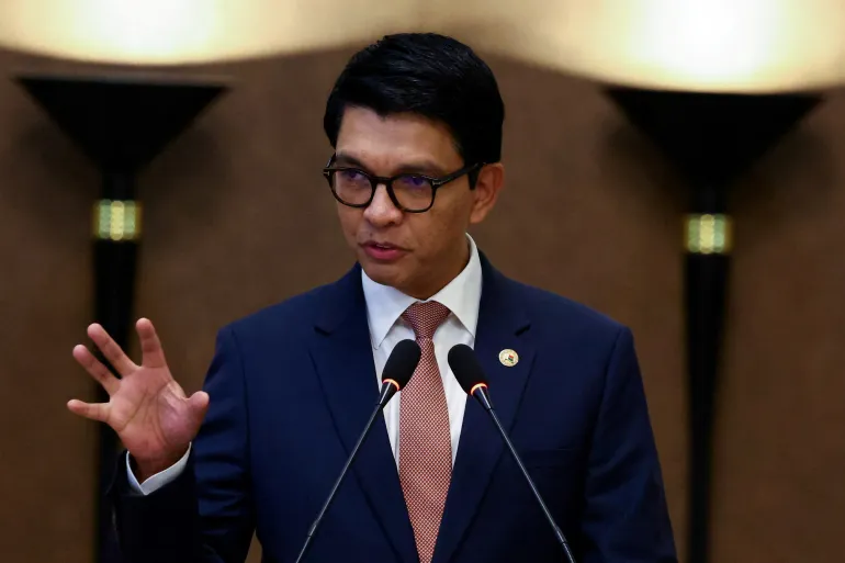Andry Rajoelina s'exprimant devant deux micros, en costume bleu et lunettes, photo d'archives