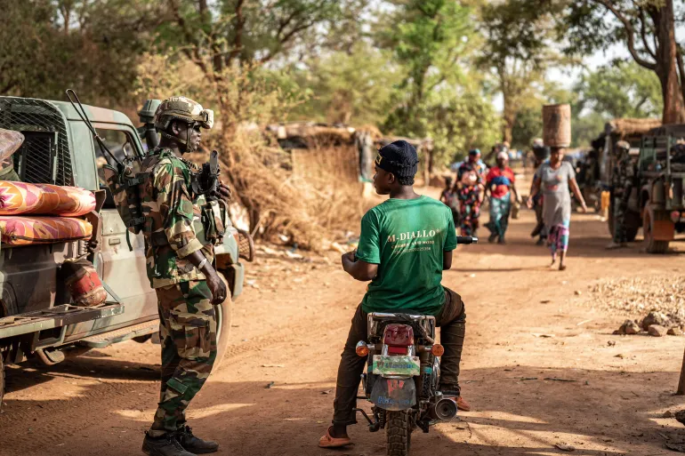 Un soldat sénégalais en tenue camouflée et casque près d'un pick-up sur une piste, image d'illustration d'archives
